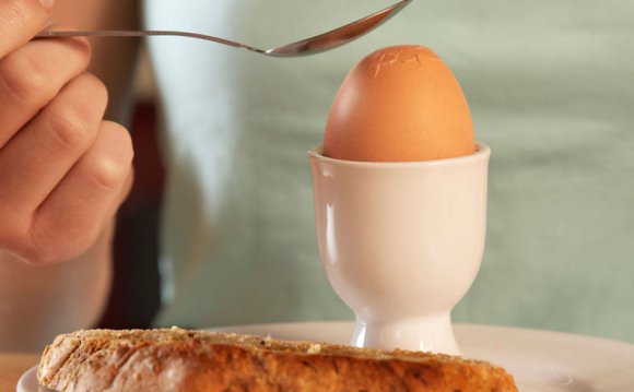 Woman cracking boiled egg