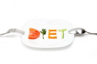 White plate with word diet composed of slices of different fruits and vegetables