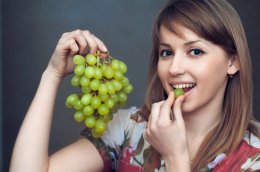 Young Woman Eating Green Grapes
